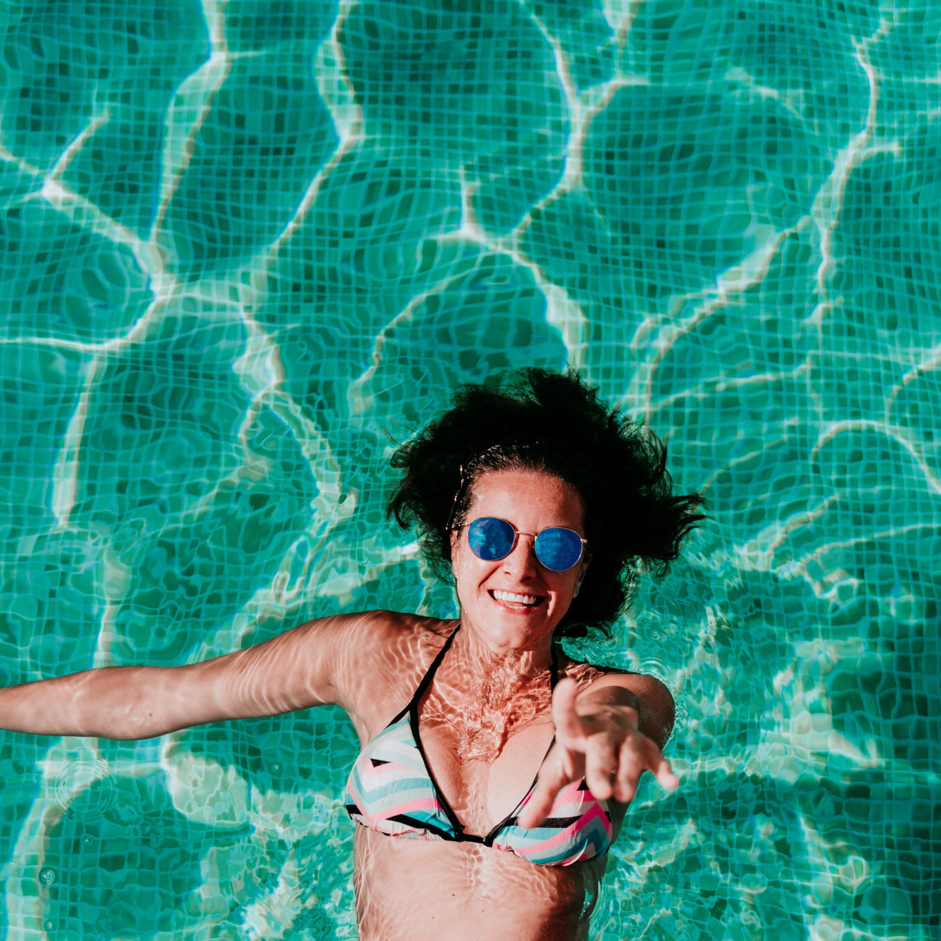 top view of happy young woman floating in a pool. summer and fun lifestyle