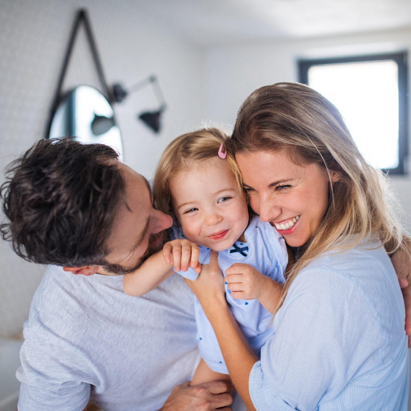 A young family with small daughter indoors in bathroom, hugging.